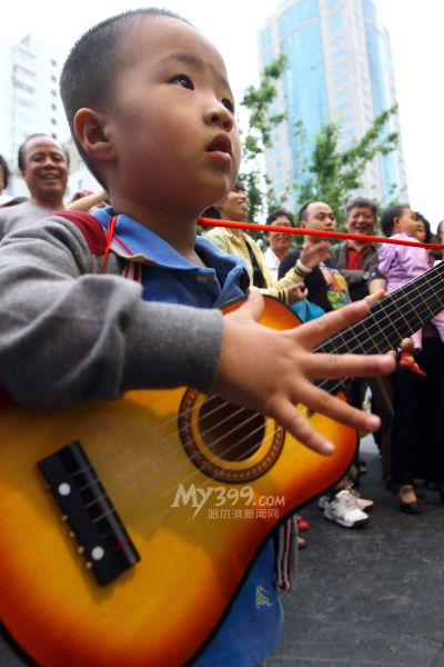 哈尔滨街头音乐节开幕 10岁少年雨中弹吉他_新